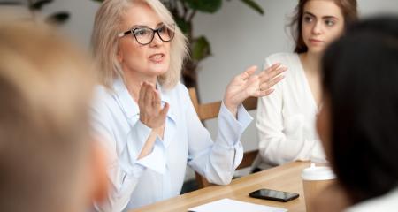 Attractive aged businesswoman, teacher or mentor coach speaking to young people