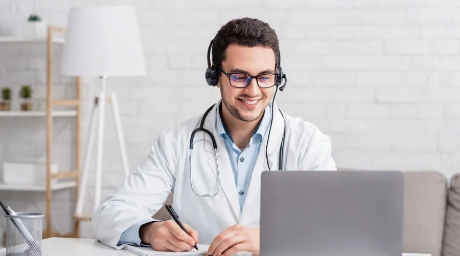 a doctor using a laptop and wearing a headset