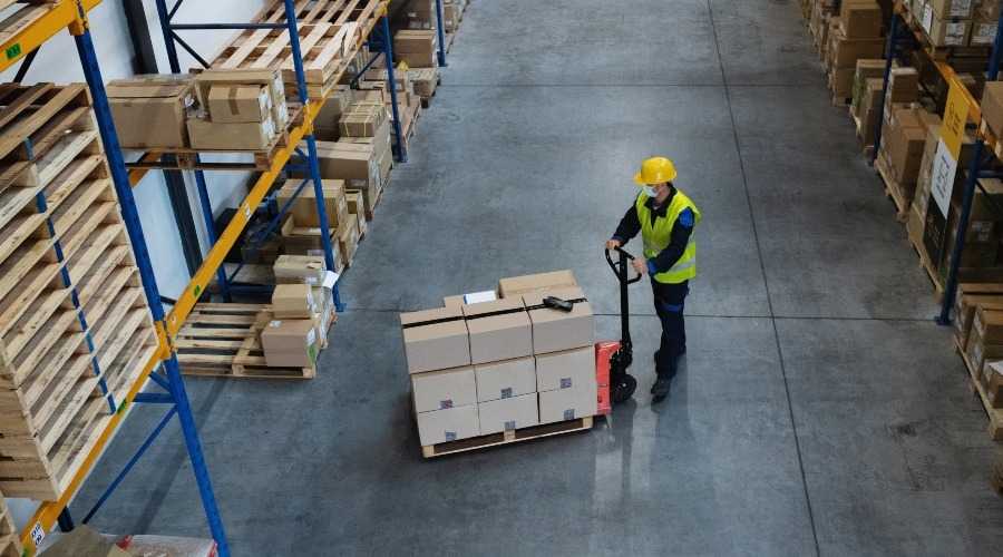 a man using pallet truck in a warehouse