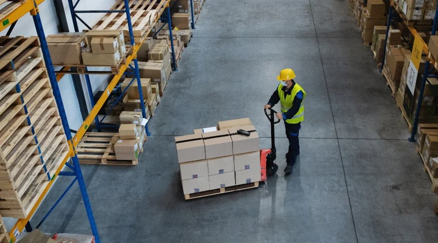 a man using pallet truck in a warehouse