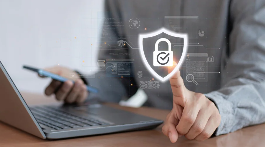 a man on a laptop touching a holographic image of a shield with a padlock in it