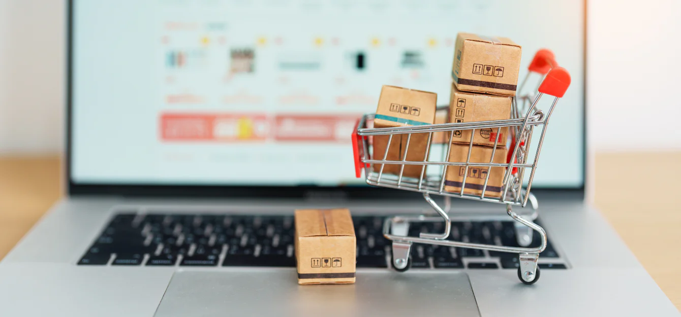 a laptop with a miniature shopping cart on top
