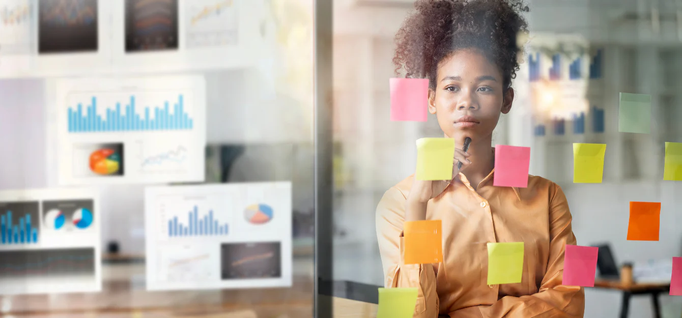 a businesswoman looking at sticky notes on a glass wall